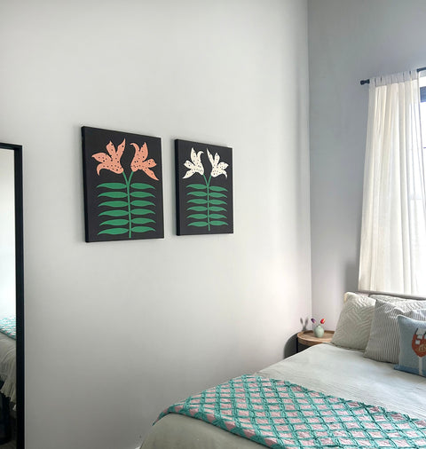 Pair of art pieces with black backgrounds featuring orange and white lily flowers with green leaves