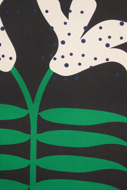 A piece of canvas contemporary art with black background featuring white lily flowers with green leaves and blue dots
