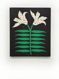 A piece of canvas contemporary art with black background featuring white lily flowers with green leaves and dark blue dots