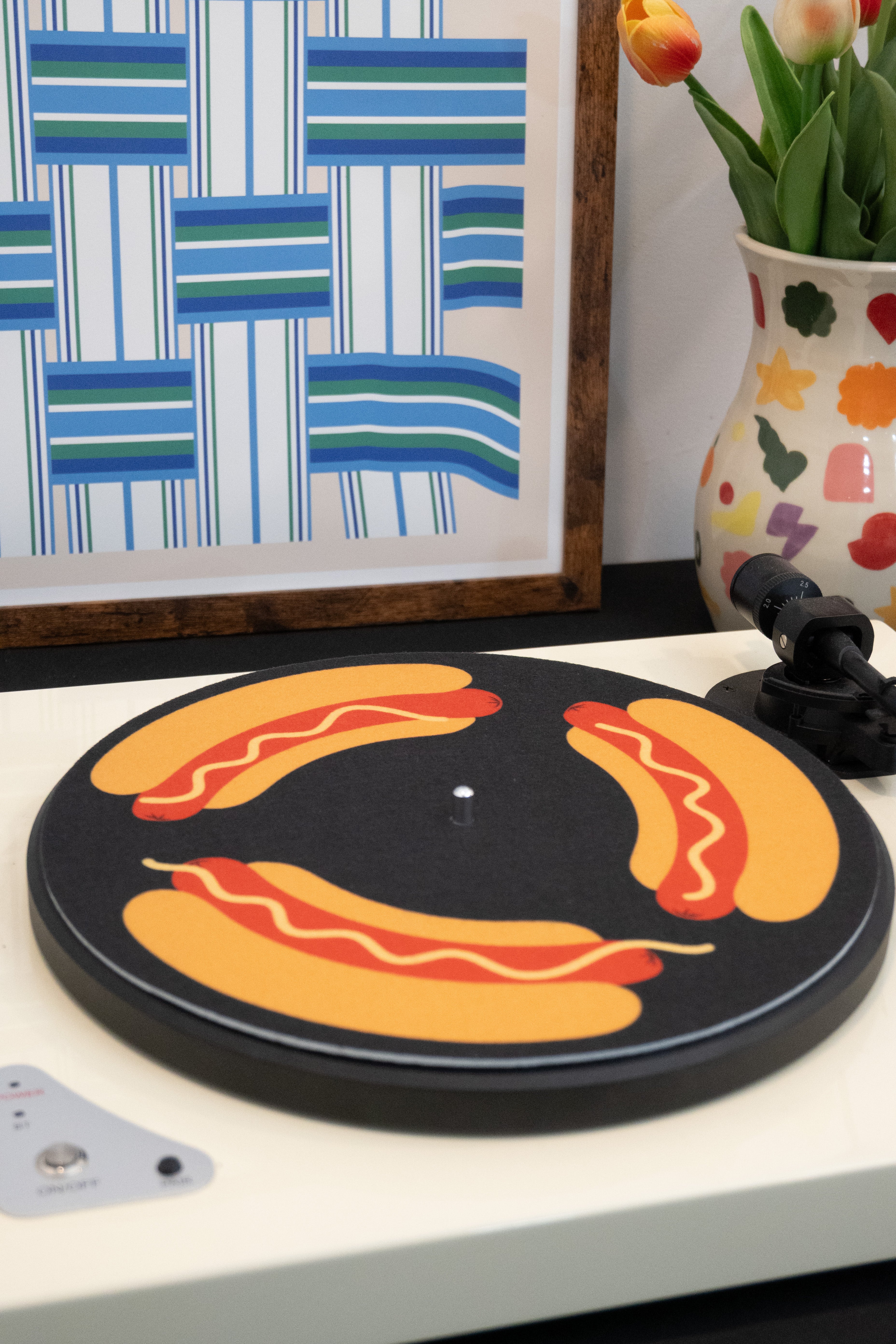 Turntable with hot dog slipmat and framed artwork in the background