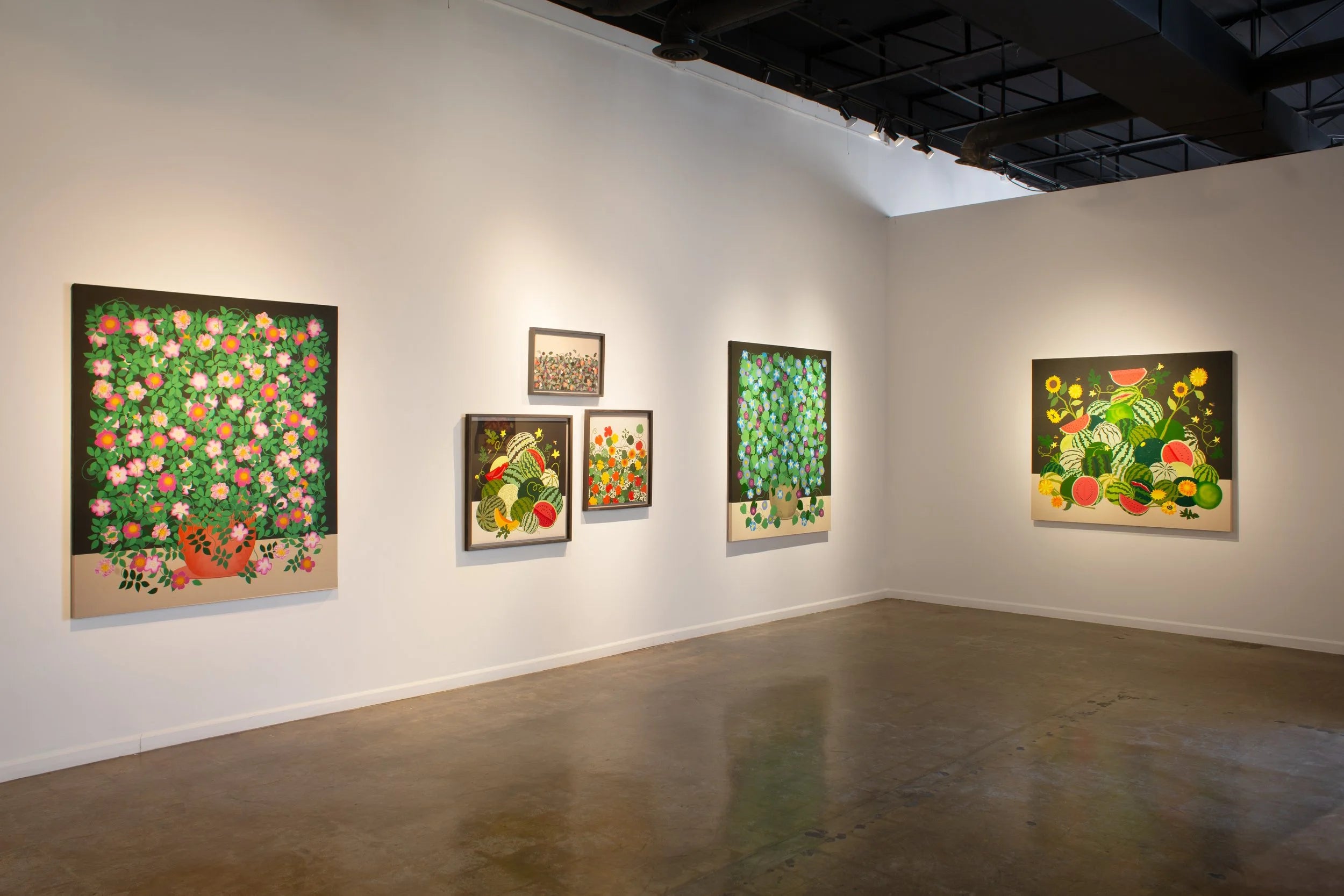Art gallery with various colorful floral and fruit paintings on white walls.