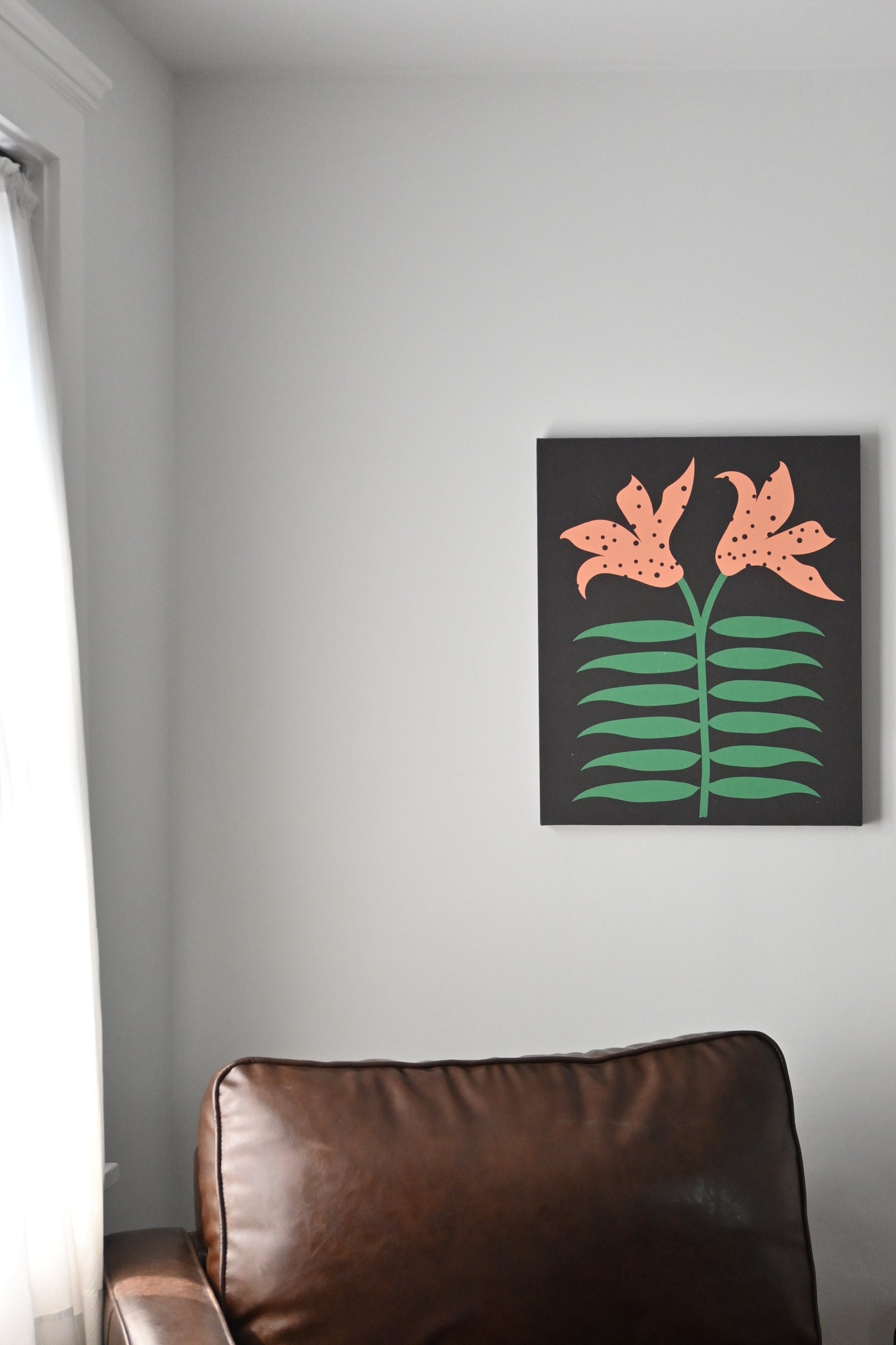 Floral lilies artwork on a wall above a brown leather chair