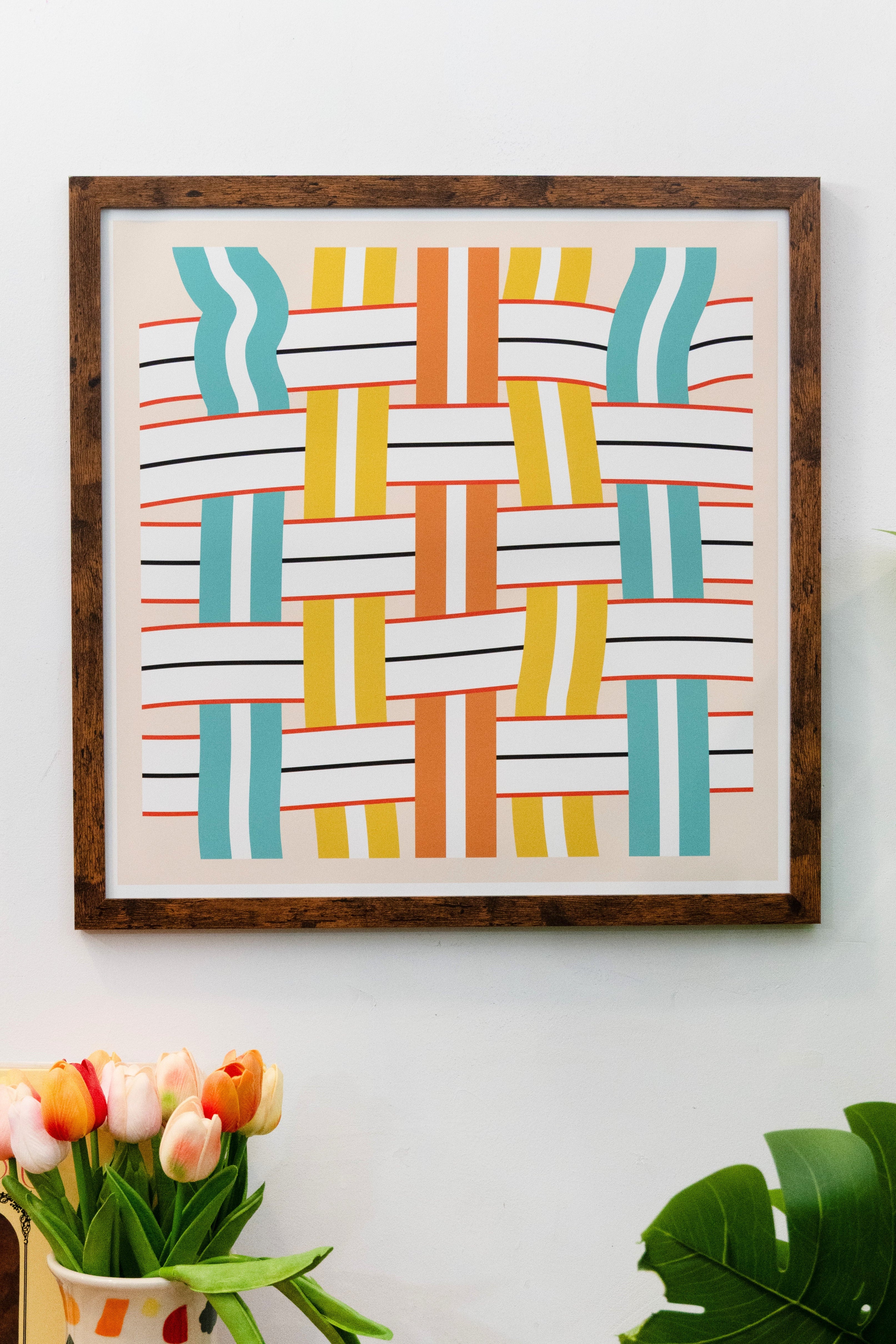 Framed multicolor orange yellow and teal geometric lawn chair pattern print with horizontal and vertical lines on a beige background with white border displayed on a white wall