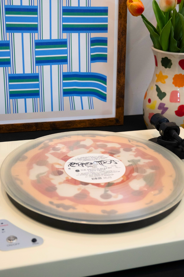 Pizza on a turntable with a colorful vase and abstract painting in the background