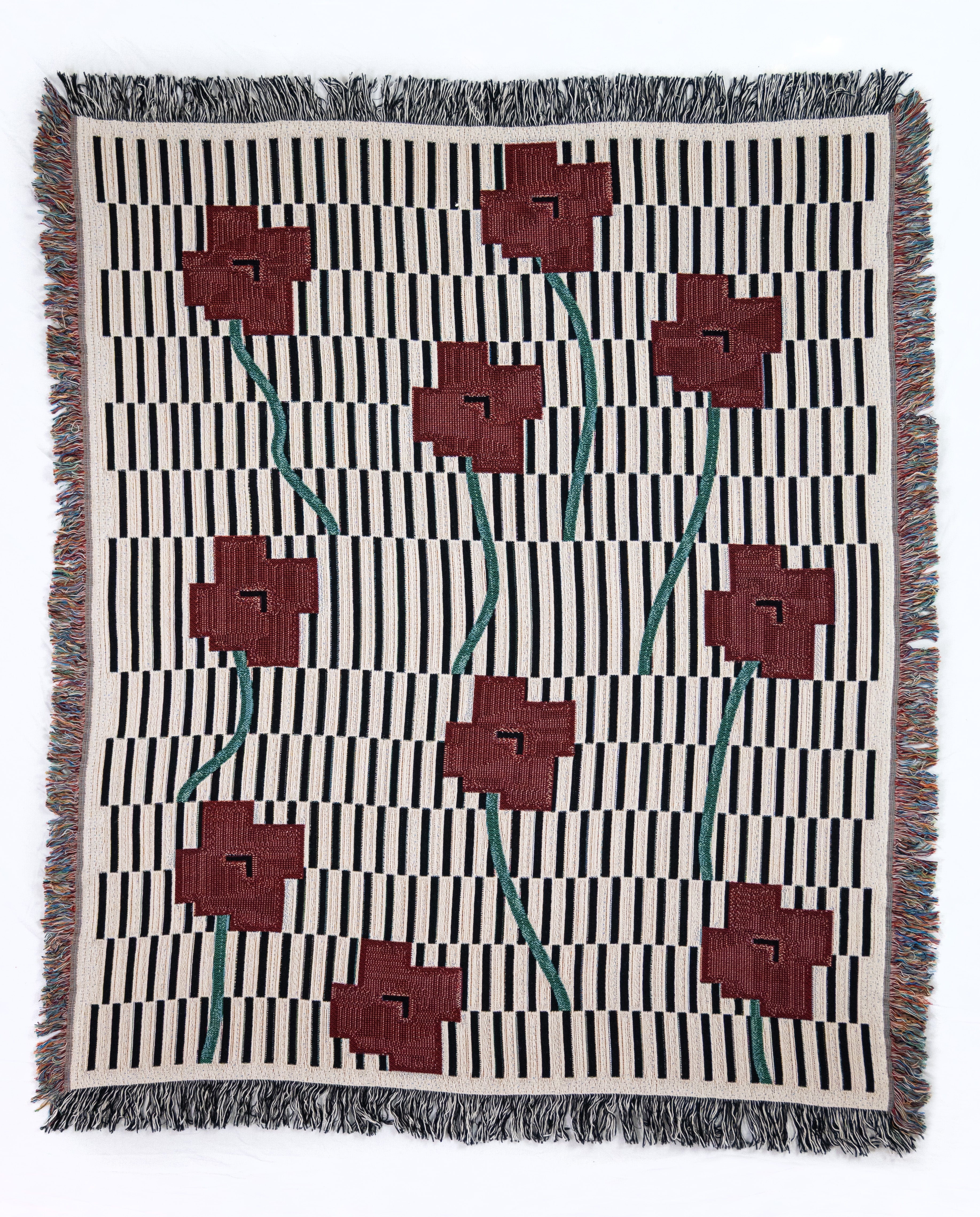 Woven blanket with geometric black and white with red and green floral pattern on a white background