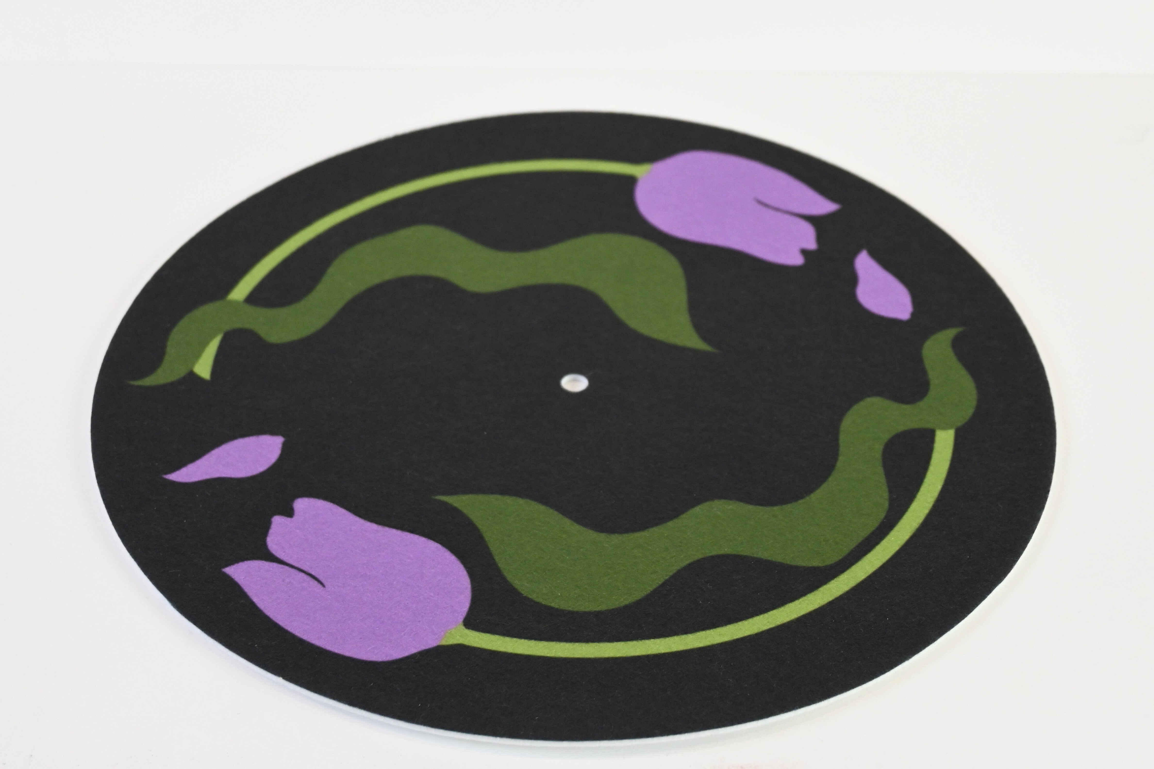 Close up of slipmat with purple tulip design on a black background with green leaves
