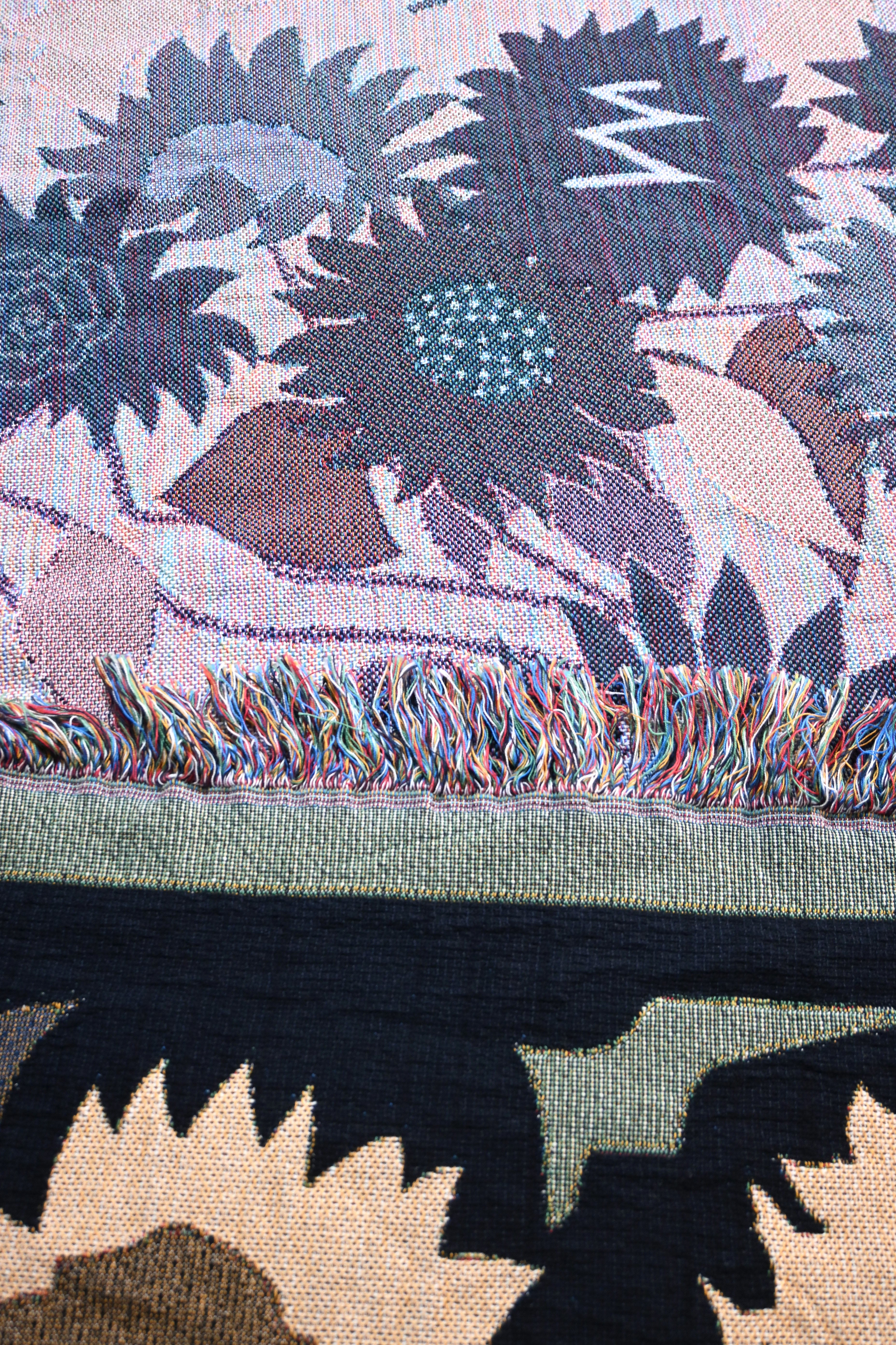 Close-up of a woven fabric with sunflower design and colorful fringe.