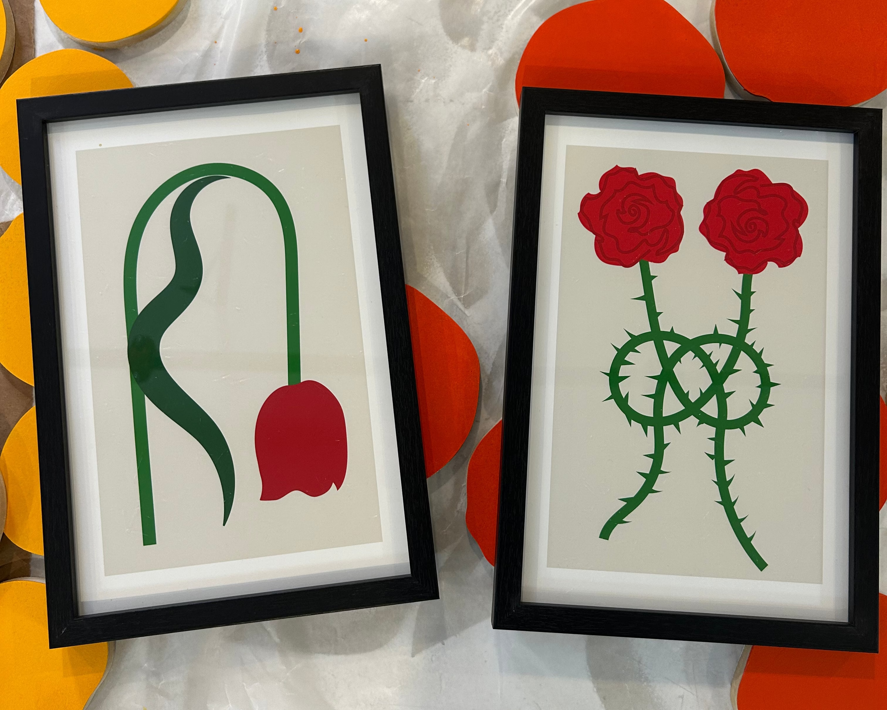 Two framed artworks of abstract floral designs on a colorful abstract background.