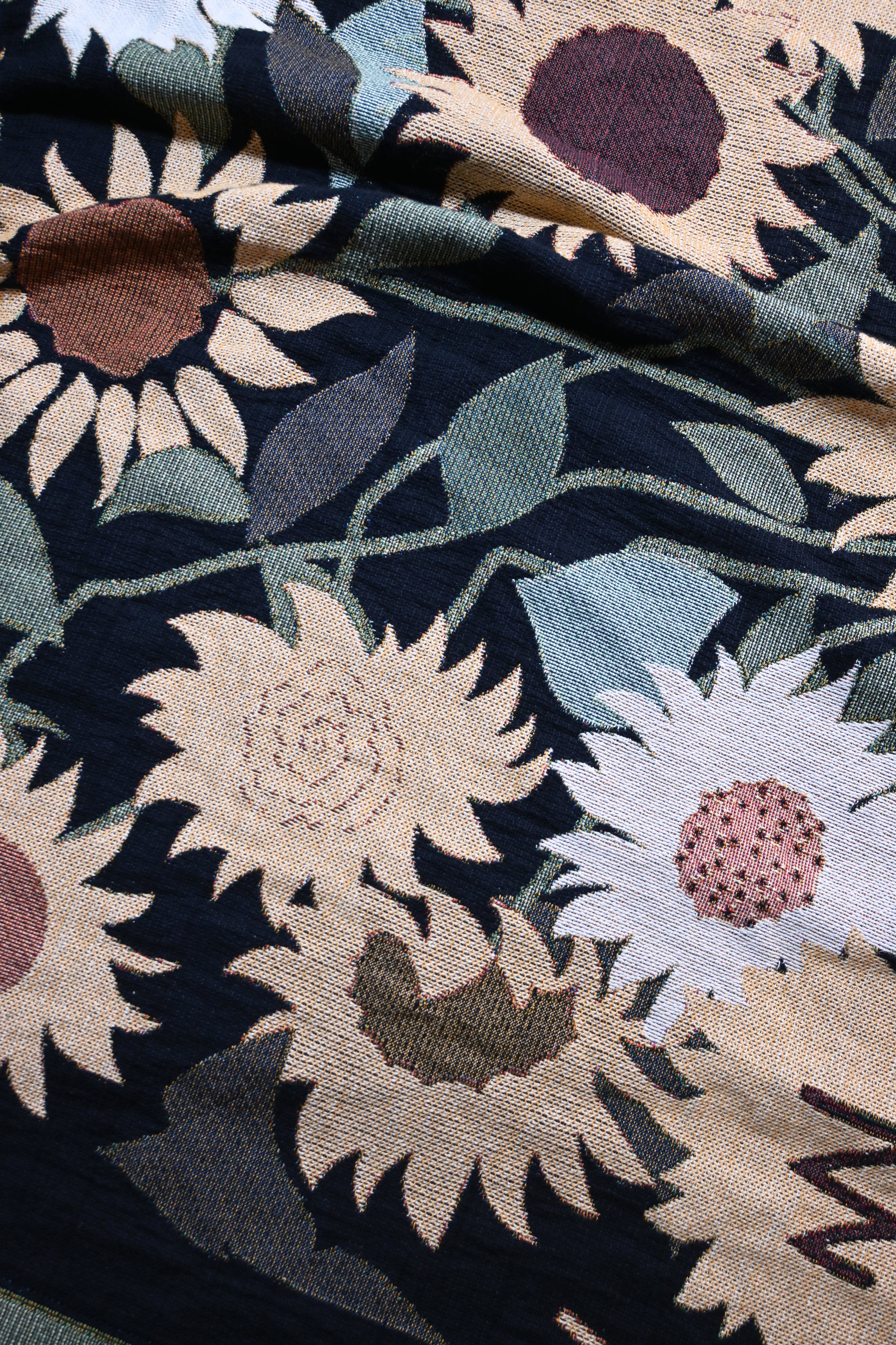 Close-up of floral woven blanket with sunflowers in various colors.