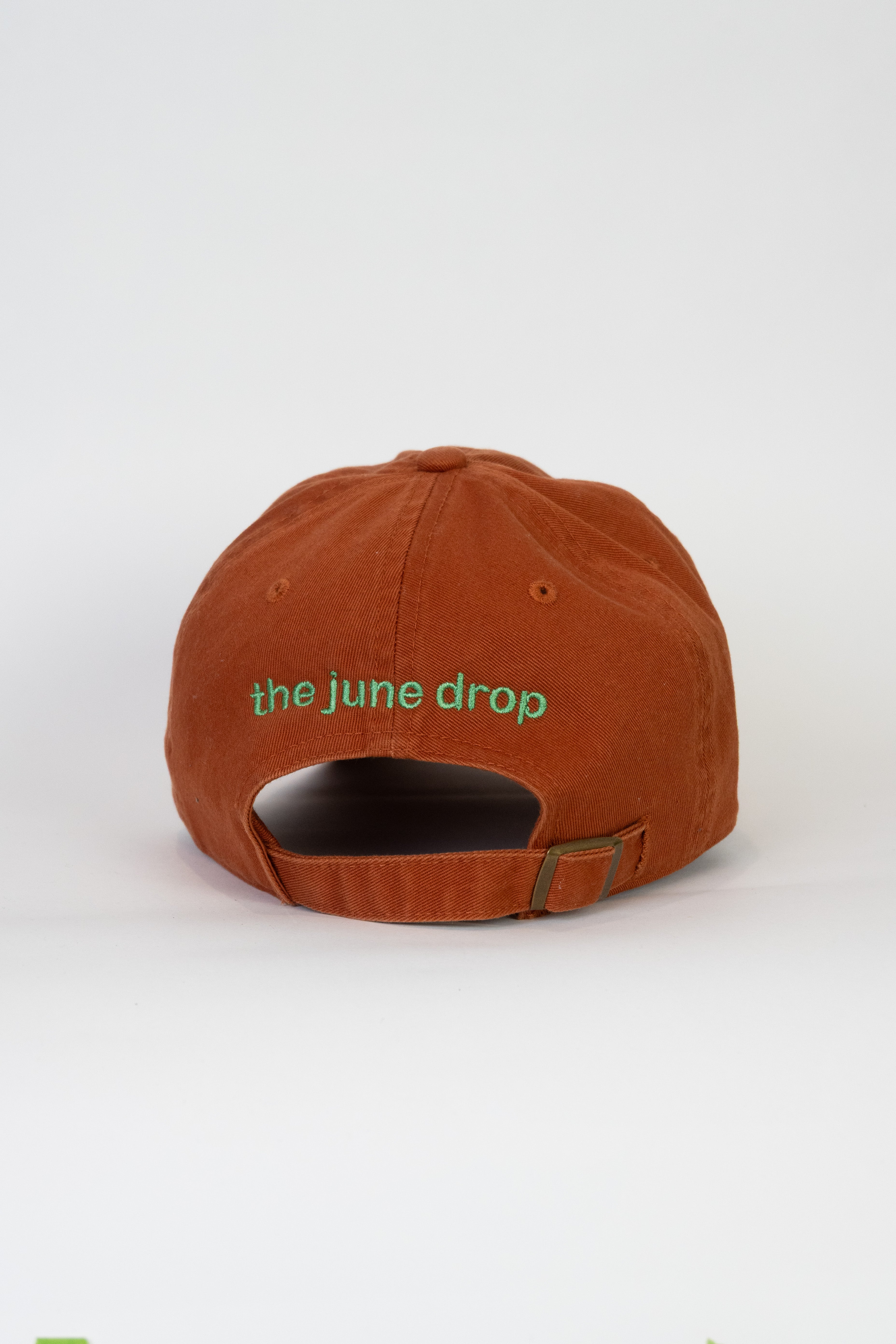 Burnt orange baseball cap with 'the june drop' thread in green
