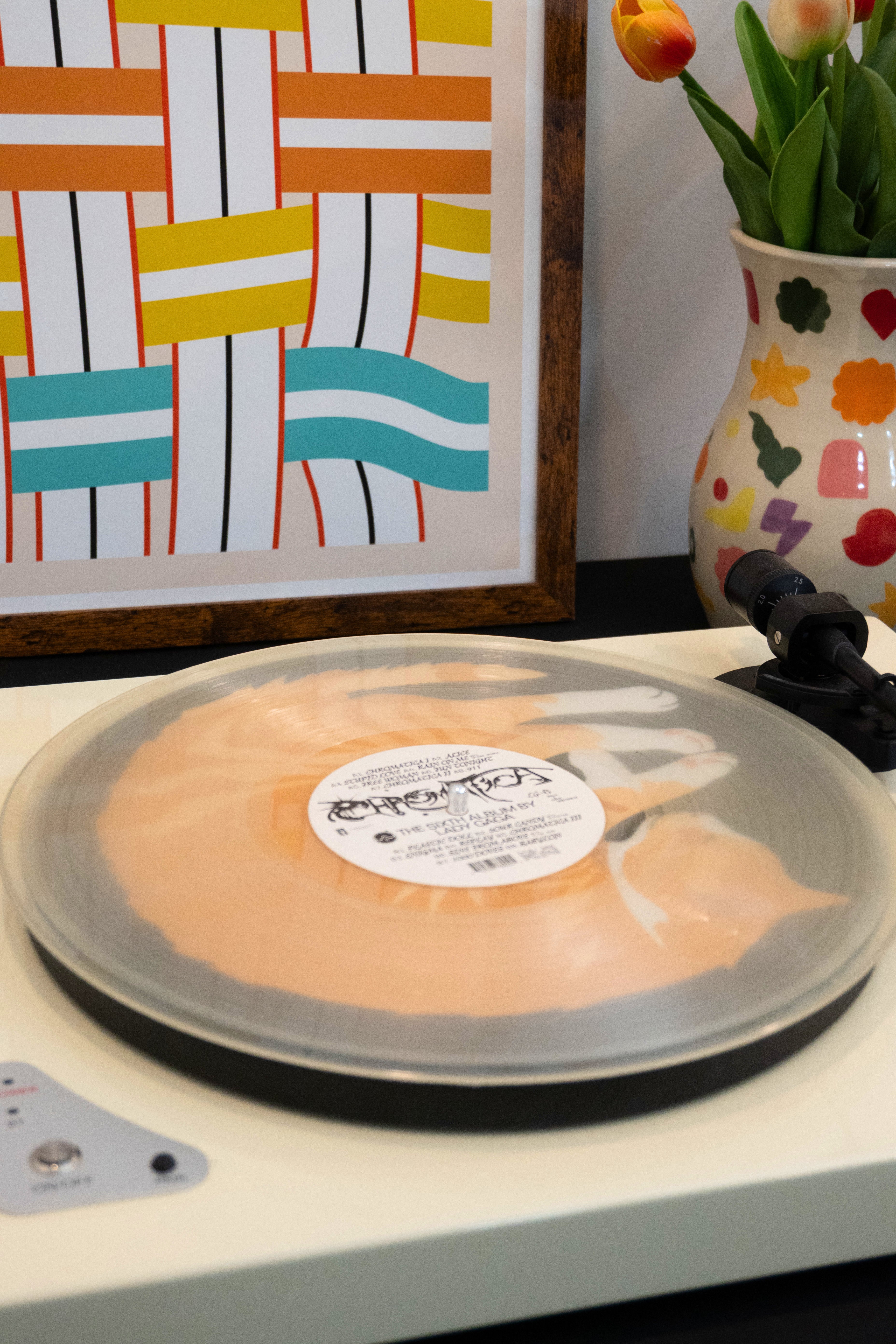 Transparent vinyl record over sleeping cat slipmat on a turntable with a colorful abstract painting in the background
