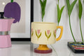 Cream colored mug with decorative tulip flowers and yellow, pink, and green colors