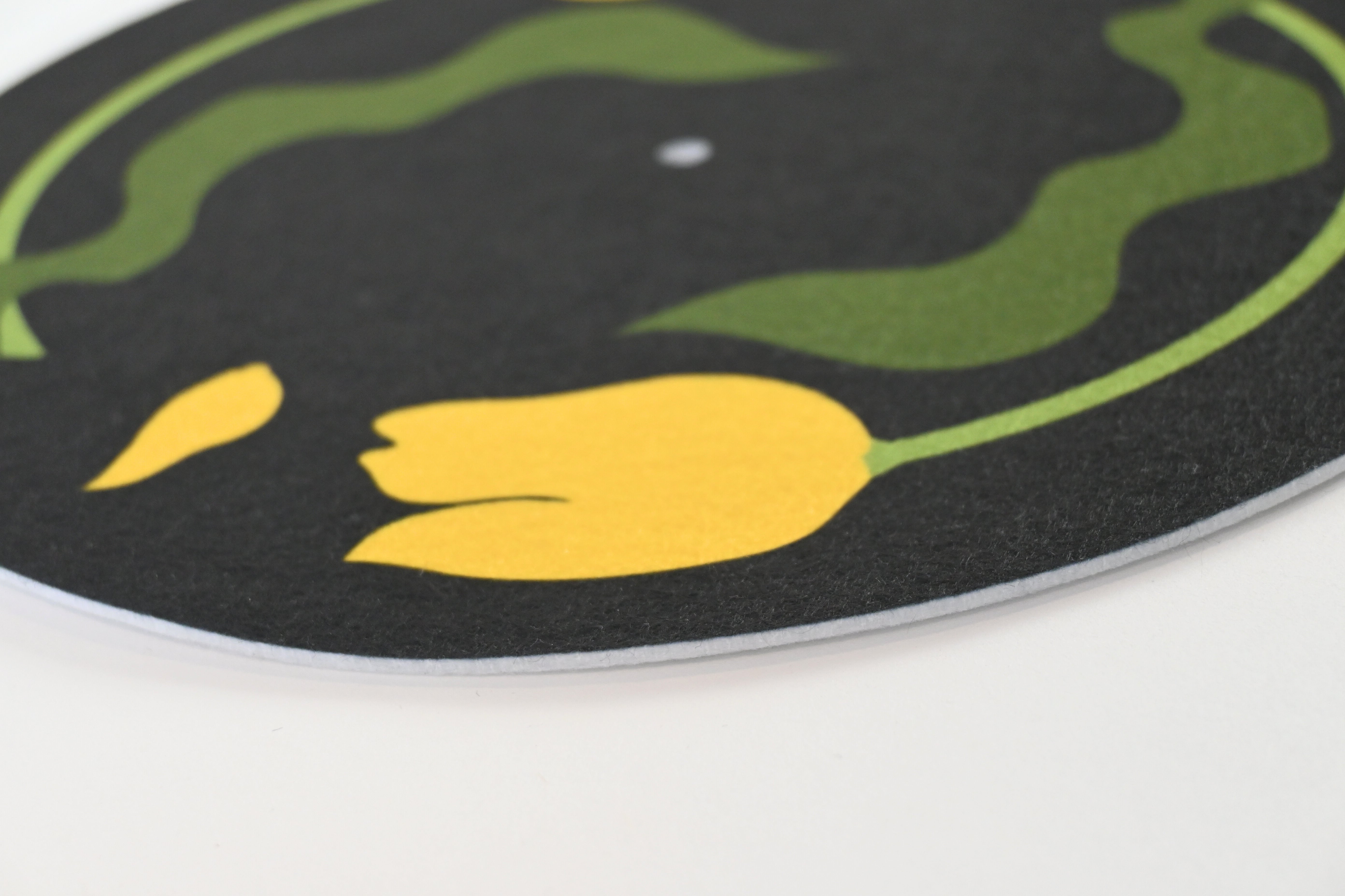 Close up of slipmat with yellow tulip design on a black background with green leaves
