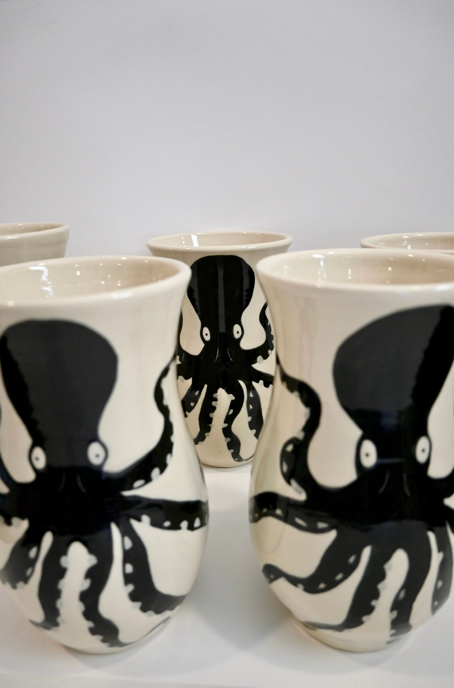 Set of ceramic vases with black octopus design on a white background