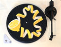 Close up of slipmat with yellow lemon twist design on a black background with green leaves